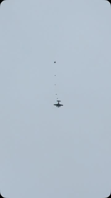 Jumper exiting the aircraft with a helicopter and canopies in the frame